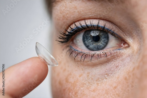 Macro shot of a person’s eye with a soft contact lens delicately placed on their fingertip, ready for insertion for better vision and correction