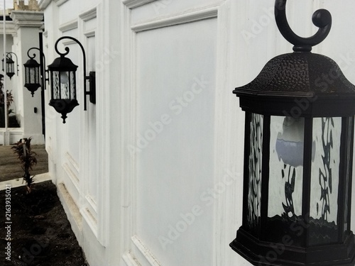 Foto A black, European-style classic wall lamp is mounted on the fence wall of a house