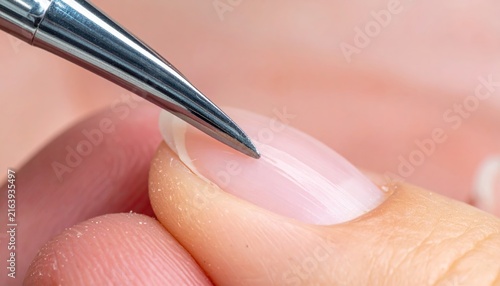 Meticulous nail care with a specialized tool gently pushing cuticles on a healthy natural fingernail. Professional manicure showing precise grooming and hygiene