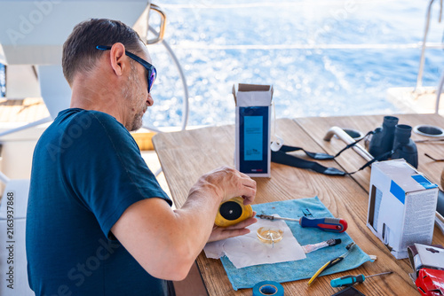 Konstfotografi Man repairing yacht equipment with hand tools during a sailing trip on the Adriatic Sea