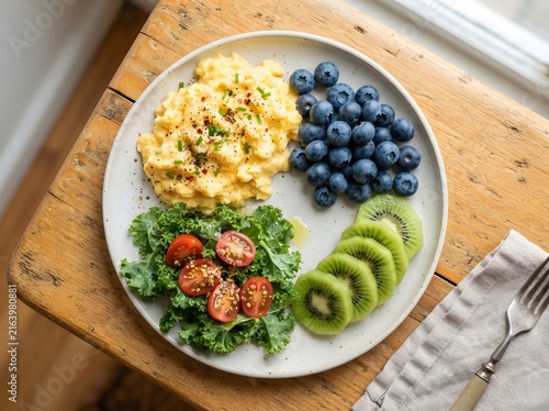 Healthy breakfast plate with scrambled eggs blueberries kiwi and salad