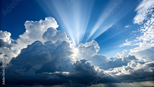 Fotografía A bright sun shining through large white clouds in a clear blue sky