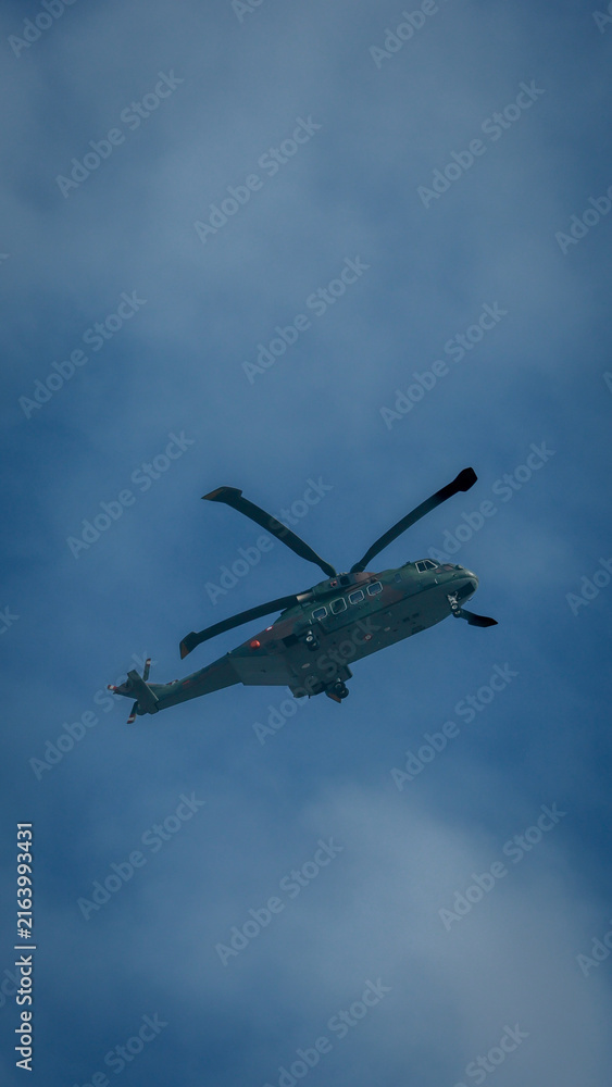 Fototapeta premium Close up Military Helicopter Flying in Blue Sky