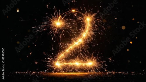 A glowing number two created with bright golden sparkler light trails