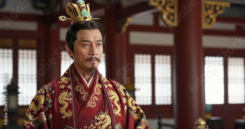 A stern-looking Chinese emperor in a room with an ancient Chinese aesthetic.