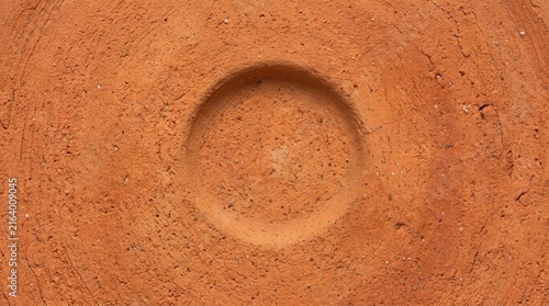 Macro shot of textured terracotta clay surface with a circular indentation or bowl shape.