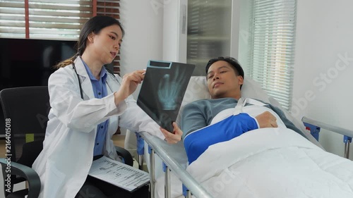 Female doctor explaining hand x ray to patient in hospital bed