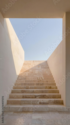 Minimal limestone staircase leading toward an open sky within a contemporary architectural space.