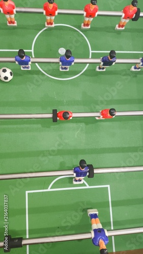 Obraz na plátně Close up view of miniature soccer players and football ball on a classic foosball table, capturing competitive gameplay, sports entertainment, recreation, teamwork, and indoor leisure activity