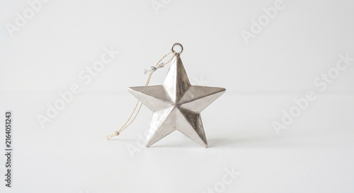 Silver metallic star ornament with a rustic string on a clean white background with subtle shadows and copy space