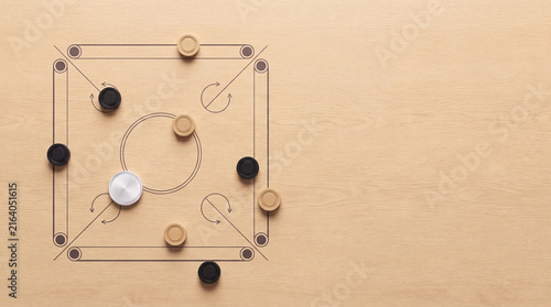 Carrom board game with wooden pieces and striker arranged on a textured