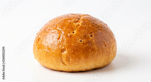 Golden brown baked bread roll or bun isolated on a clean white background with a glossy crust and subtle texture perfect for food photography