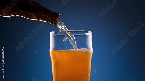 Golden craft beer pouring from dark glass bottle into a clear pint glass