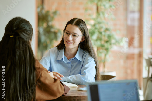 Diverse young adult female students studying together at university campus cafe. Image represents peer learning and is suitable for higher education marketing campaigns