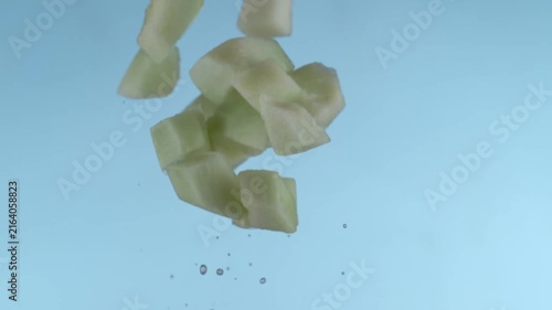 Green Melon Cubes Falling Downward Against A Light Blue Background