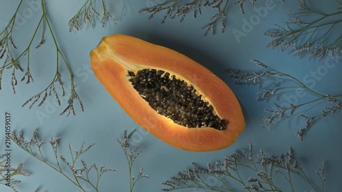 Half Ripe Papaya with Seeds on Blue Background with Floral Flat Lay Design