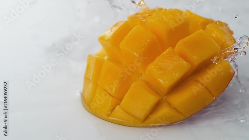 Juicy cubed ripe mango fruit piece refreshing water splash on white background