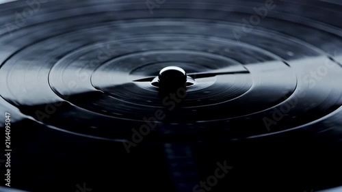 Close-up view of a vinyl record spinning on a turntable, showcasing the smooth surface and central spindle as it rotates in a dimly lit environment