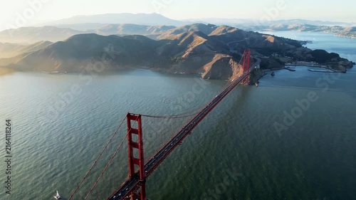 Aerial view of golden gate bridge with traffic flowing over suspension structure and sausalito hills in background.