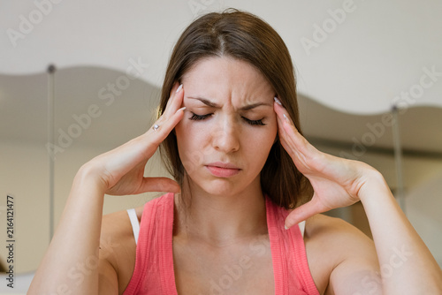 Cuadro en lienzo Close up portrait of a young caucasian woman suffering a headache with a frown and hands on her temples, for migraine, pain relief and head massage content