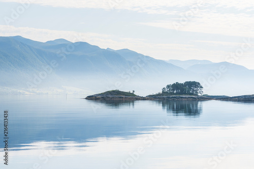 Фотография Little mist over still lake in Norway with mountains and trees in focus