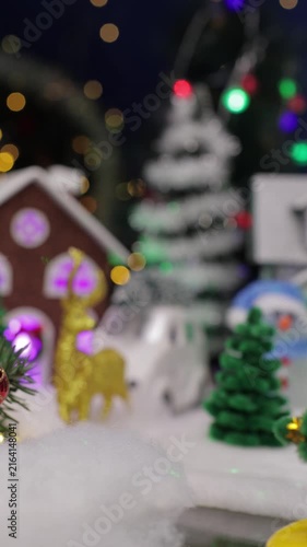 Ahead of the Christmas village there is a yellow car with a Christmas tree on the roof