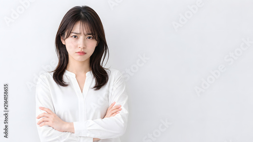 Plakat 腕を組んで不満そうな表情を見せる白いブラウスの若い日本人女性