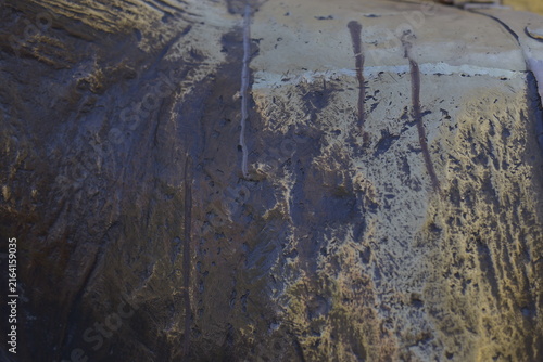 A close-up abstract texture of a metallic surface with horizontal ridges and grooves, illuminated by warm bronze and cool blue reflections.