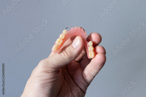The doctor holds a removable clasp prosthesis in his hands.