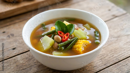 Sayur asam, a traditional Indonesian dish featuring a mix of various vegetables—such as corn, chayote, long beans, and other legumes—seasoned with tamarind. It is served in a white bowl.