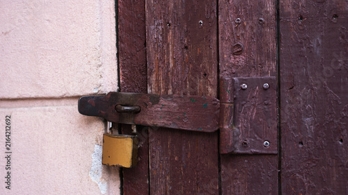 Foto Old brown wooden door locked with a metal padlock on a rusty latch