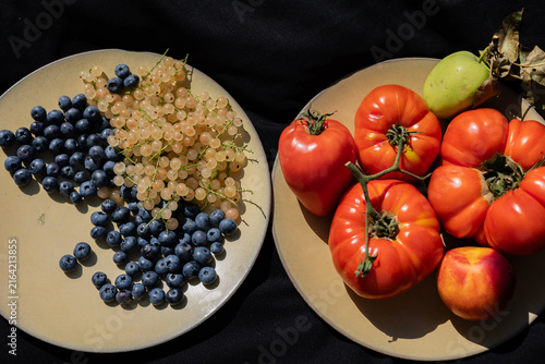 Fresh tomatoes, blueberries and white currants on plates