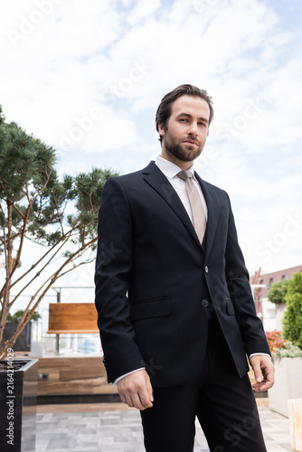 Foto A handsome man in stylish suit standing on a rooftop terrace, radiating confiden
