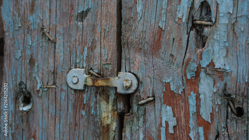 Konstfotografi Old weathered wooden door with flaking light blue paint and a rusty metal padlock hasp