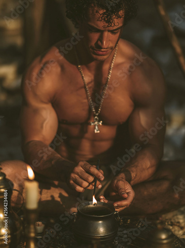 Man Performing Candle Ritual with Cauldron in Warm Light