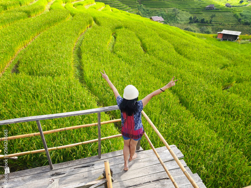Asian tourist woman raising her arms at the terraced rice fields at northern mountain of Thailand.