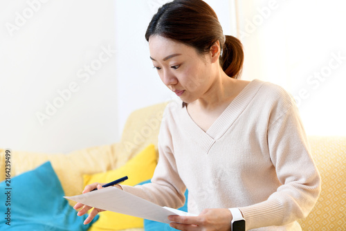 自宅のリビングで書類を書くアジア人の女性