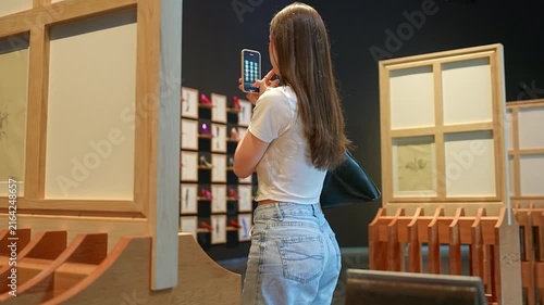 Young woman taking picture with smartphone in art museum