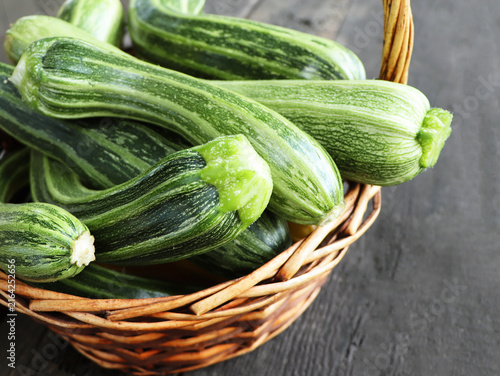 Fresh Zucchini in Wicker Basket on Dark Wooden Table
