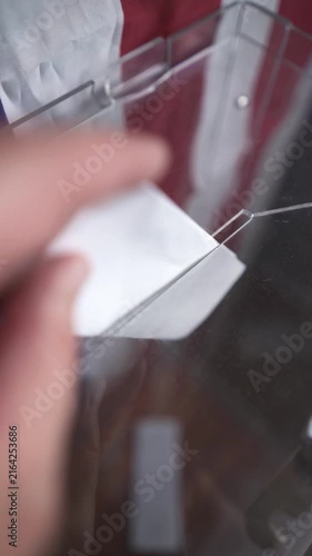 POV of citizen walking up and dropping folded ballot into box with US flag background