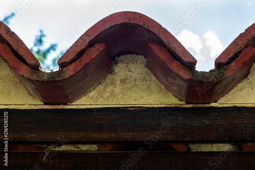 Old roof tiles on top of a stone fence - front view of shape and construction. Adobe RGB color profile. Real photo.