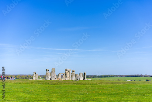 Stonehenge, prehistoric stone circle on Salisbury Plain in Wiltshire, England seen from the distance with a group of people on the left