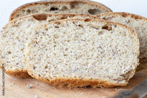 Homemade bread slices on a cutting board with white background. Close-up.