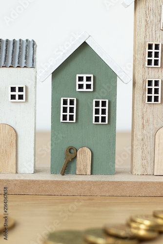Miniature houses, key, and coins with white background. Real estate prices, mortgage cost, buying and selling property concept.
