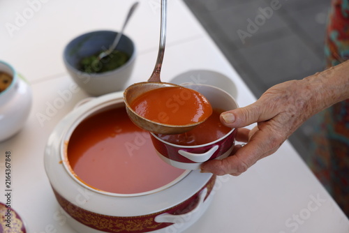 Foto Grand-mère servant un gaspacho maison à la louche