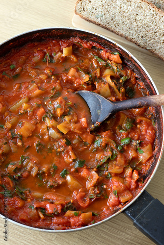 Homemade tomato pepper sauce in a cooking pan with wooden spoon. Top view.