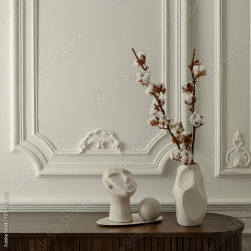 Minimalist interior decor with abstract white ceramic sculpture and cotton branch in vase against classic wall molding background for home design