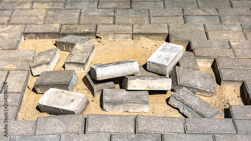 Foto Bricks lay scattered on sand in a gap of a paved surface