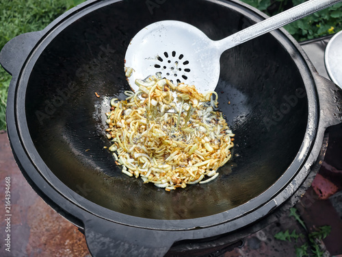 Foto In a garden, a person stirs fried onions and spices in a kazan over an open flam