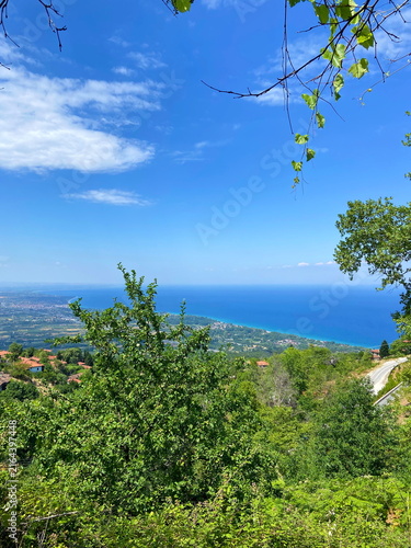 Fotografie Unsurpassed panorama from the thickets of the mountain forest of the lush blue of the Aegean Sea on the horizon with coastal settlements on the slopes of the mountain hills